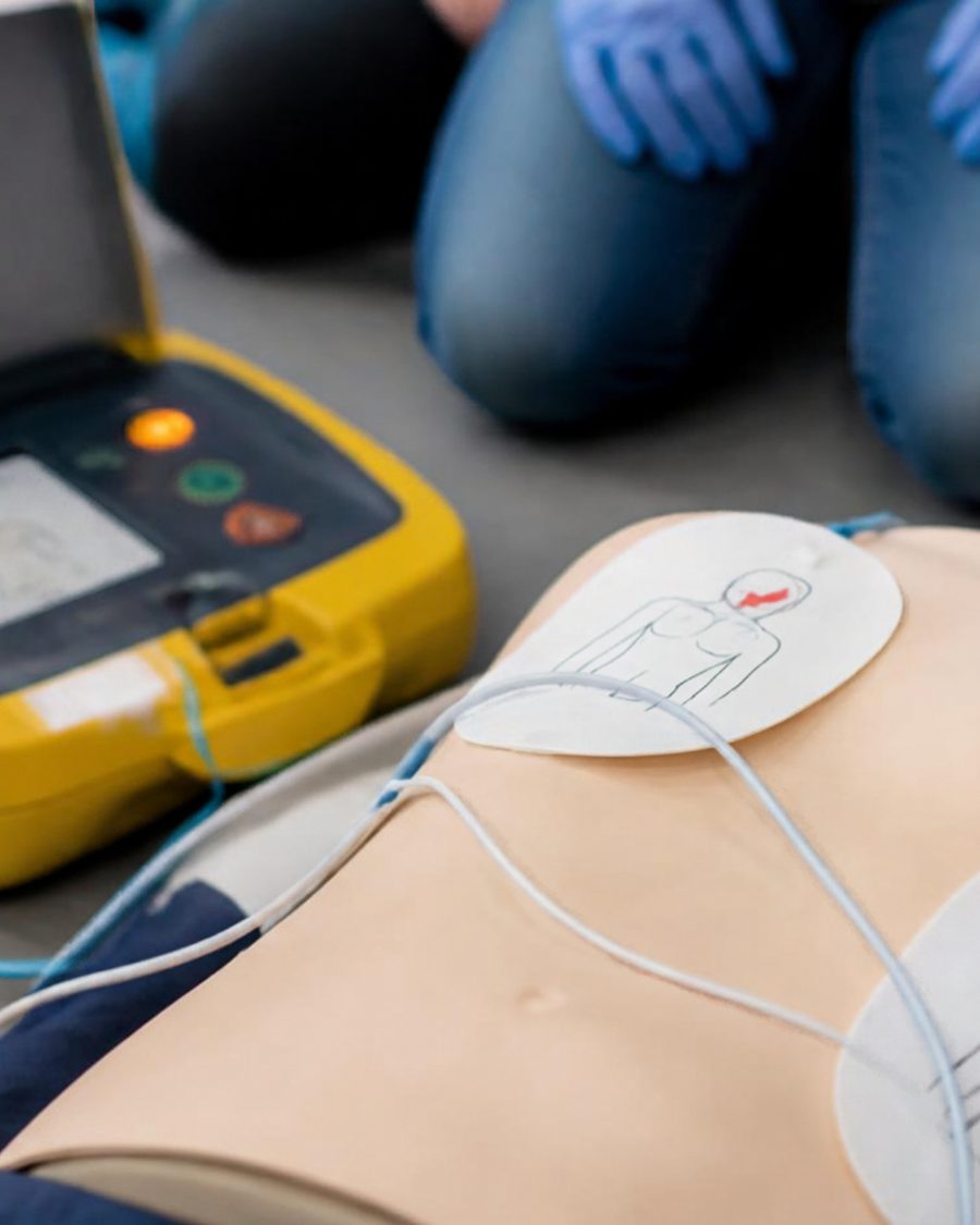 Defibrillator mit aufgeklebten Elektroden an einer Übungspuppe.